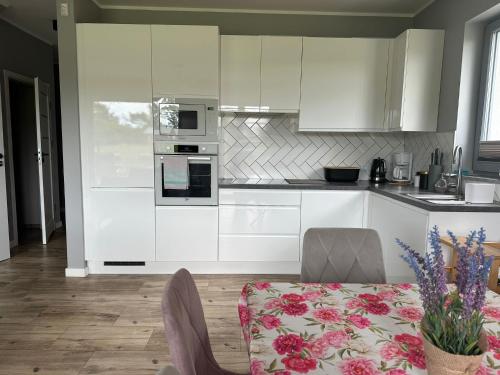 a kitchen with white cabinets and a table with a tablecloth at Domy wakacyjne WELLE in Kołczewo