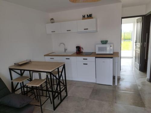 une cuisine avec une table et des chaises et un micro-ondes dans l'établissement Meublé Côte d'Opale, à Saint-Folquin
