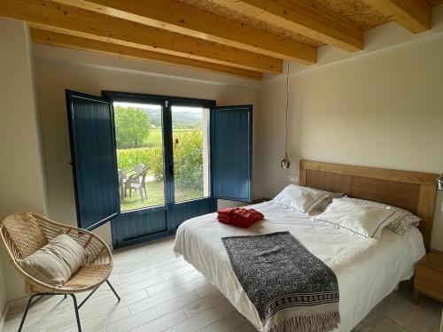 a bedroom with a bed and a chair and a window at Grandes Duplex nuevos con Jardin - 3 llaves, Los Gayoles Rural in Castropol