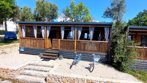 a small cabin with a bench and a table and two bikes at MOBILE HOMES SELCE - ALPE JADRAN MOBIL 641 in Selce