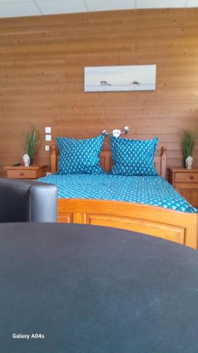 a wooden bed with blue pillows in a room at Le Domaine in Moustey