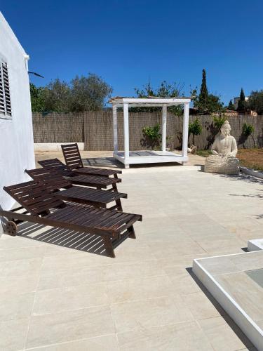 a patio with two wooden chairs and a statue at Villa Air - Relax, close to bossa beach, spacious rooms and private pool in Sant Jordi
