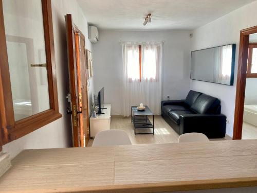 a living room with a black leather couch and a tv at Villa Air - Relax, close to bossa beach, spacious rooms and private pool in Sant Jordi