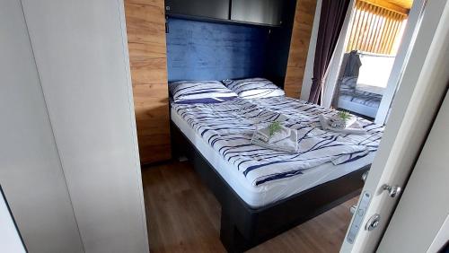 a bed in a small room with a blue headboard at MOBILE HOMES SELCE - ALPE JADRAN MOBIL 641 in Selce