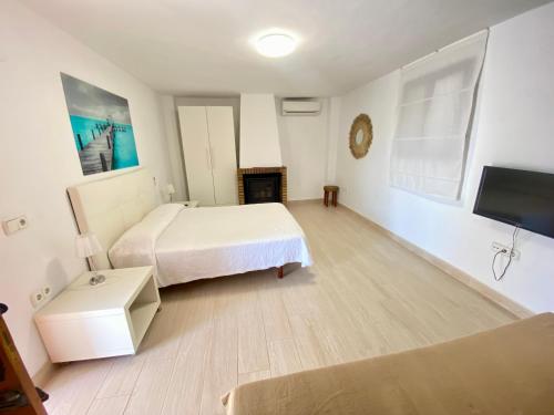 a white bedroom with a bed and a tv at Villa Air - Relax, close to bossa beach, spacious rooms and private pool in Sant Jordi