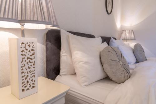 a white couch with pillows and a lamp on a table at Bankton Rooms & Lodges in Livingston