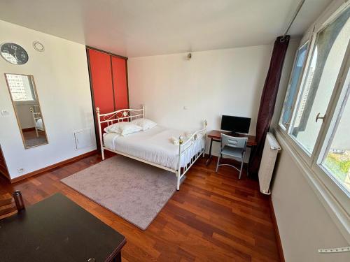 ein Schlafzimmer mit einem Bett und einem Schreibtisch mit einem Computer in der Unterkunft Studio with Panoramic View: Live in Peace! in Paris