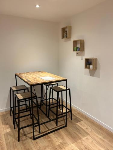 a table with four stools in front of a wall at Appartement Armentières proche gare in Armentières