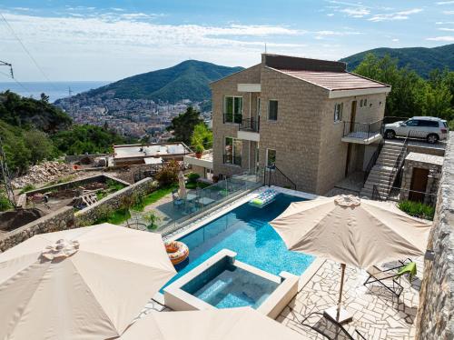 a house with a swimming pool and two umbrellas at Ventus Rosa Villa in Budva
