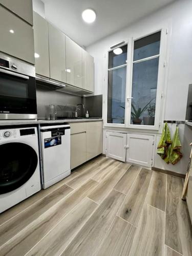 une cuisine avec des appareils blancs et un parquet dans l'établissement Au coeur du marché Poncelet et à 2 pas de l'Arc de Triomphe - appartement 6 personnes et 1 bébé, sdb, 2 WC, à Paris