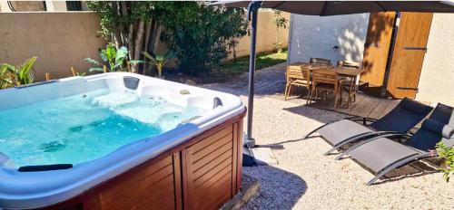 bañera de hidromasaje con sombrilla, mesa y sillas en Maison & SPA, Terrasse & Jardin, Parking, en Plan-de-Cuques