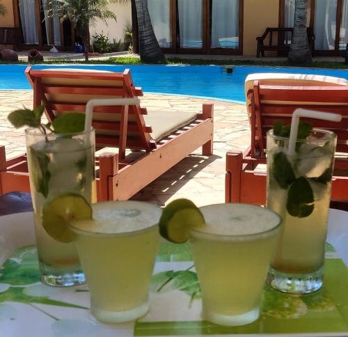 einen Tisch mit 3 Gläsern Limonade und einem Pool in der Unterkunft Kites Mancora in Máncora