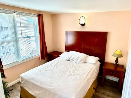 a bedroom with a bed with a red headboard and two windows at Atlantic Breeze Motel & Apartments in Ocean City