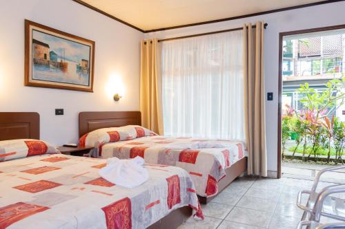 Habitación de hotel con 2 camas y ventana en Hotel Arenal Rabfer, en Fortuna