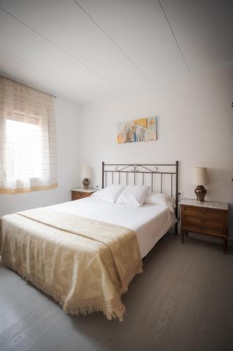 a white bedroom with a large bed and a window at El Solell de l'àvia in Olot