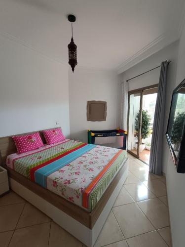 a bedroom with a bed with pink pillows at Appartement de vacances BERALMAR CHEZ HOUDA in Asilah