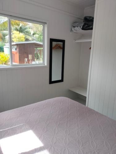 a bedroom with a bed with a mirror and a window at Oronga Beach in Arorangi