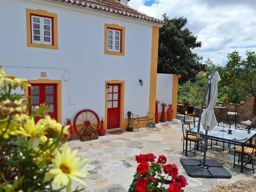 馬夫拉的住宿－Casa das Janelinhas - Cottage near Sintra, Mafra, Ericeira，房屋设有带桌子和遮阳伞的庭院