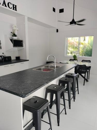 a kitchen with a counter with stools and a sink at Oronga Beach in Arorangi