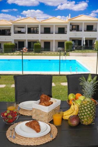 a table with plates of food and fruit next to a pool at Casa Santos in Albufeira