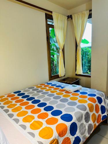 a bed with an orange and blue comforter in a bedroom at La Casa de Cecilia Mindo in Mindo