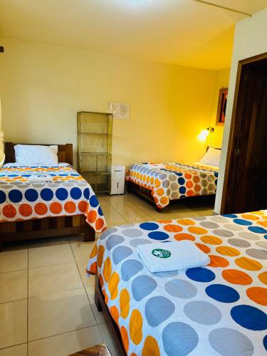 a room with two beds with orange and blue at La Casa de Cecilia Mindo in Mindo