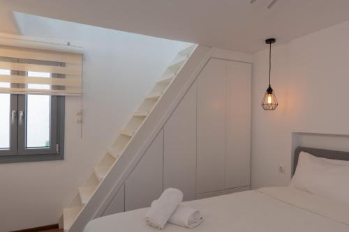 een witte slaapkamer met een trap en een bed bij Cozy Residence in Astypalaia-stad (Chora)