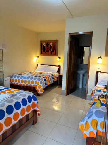 明多的住宿－La Casa de Cecilia Mindo，一间客房配有3张橙色和蓝色的床