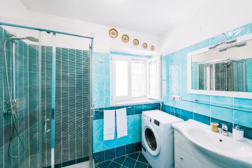 La salle de bains est pourvue de carrelage bleu, d'un lavabo et d'un lave-linge. dans l'établissement Sea view - Ravello houses, à Ravello
