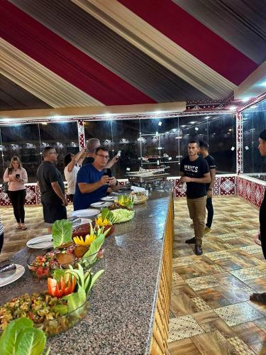 a group of people standing around a buffet line with food at Nasa desert luxury camp in Wadi Rum