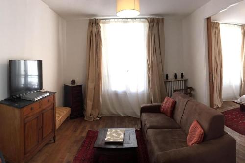 un salon avec un canapé et une télévision dans l'établissement Charmant Appt 2/4 pers Quartier Père Lachaise, à Paris