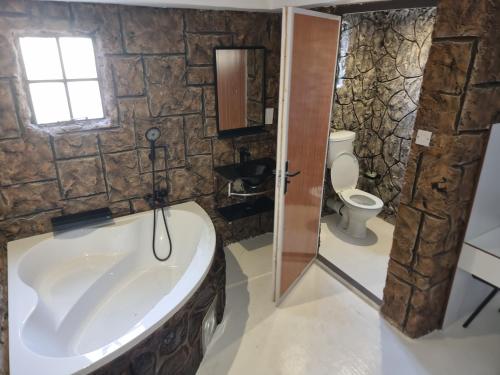ein Badezimmer mit einer großen Badewanne und einem WC in der Unterkunft Rustiek Hotel in Kasane