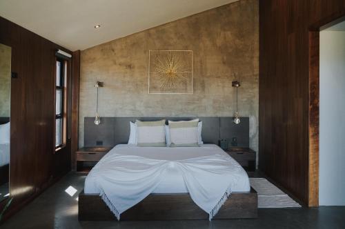 a bedroom with a large bed with white sheets at Bajo Estrellas Hotel Contemporáneo in Valle de Guadalupe