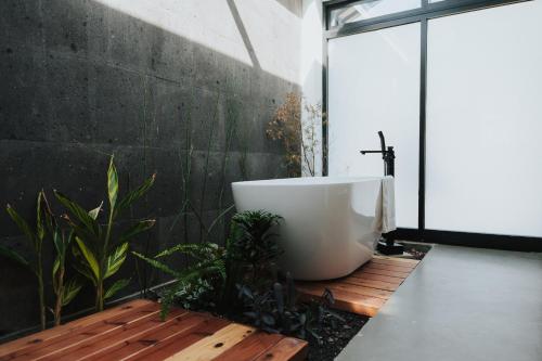 a bathroom with a large white bath tub on a wooden floor at Bajo Estrellas Hotel Contemporáneo in Valle de Guadalupe