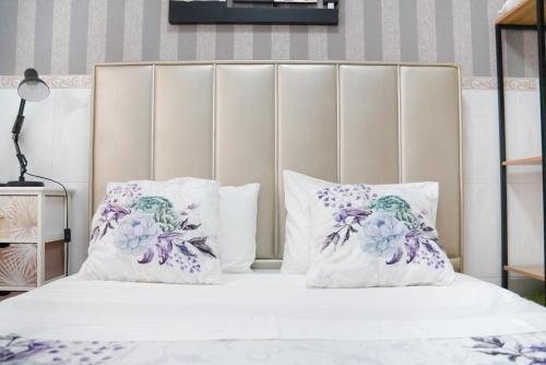 Una cama con almohadas moradas y blancas. en Dina Beach House Quinzico, en Nazaré