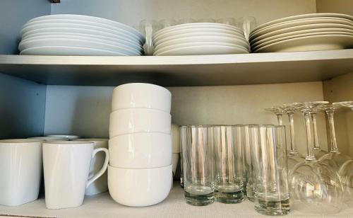 a shelf with plates and cups and glasses on it at Carré Vert Guadeloupe Villa Privée Piscine in Gourbeyre