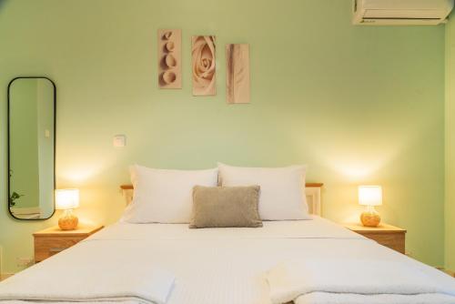 a bedroom with a large white bed with two lamps at Kantounata Apartment in Lefkímmi