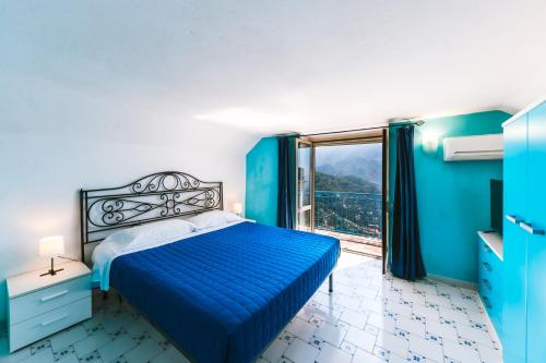 a blue bedroom with a bed and a window at Sea view - Two bedroom - Ravello houses in Ravello