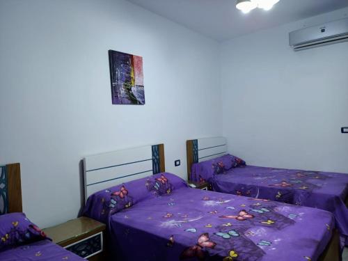 2 camas en una habitación con sábanas moradas en Palmera Beach, en Ain Sokhna