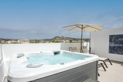 a hot tub on a balcony with an umbrella at JnS Premium Stay in Faliraki
