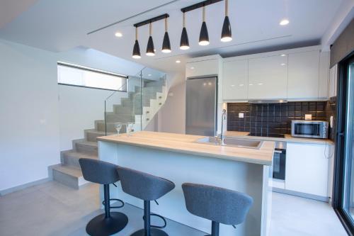 a kitchen with a counter with two chairs and a sink at Mylos ridge villas - ORION in Agios Nikitas