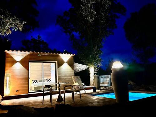 une petite maison avec des chaises et une piscine la nuit dans l'établissement Les Bergeries de Figari, à Figari