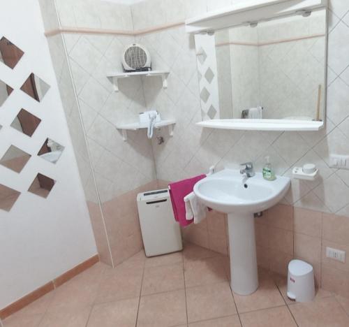 uma casa de banho branca com um lavatório e um espelho em casa camelie em Pino Lago Maggiore