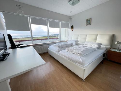 Cama blanca en habitación con escritorio y ventanas en House in Akranes - Birta Rentals en Akranes