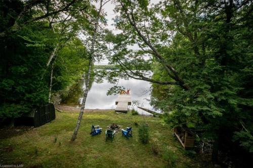 a group of picnic tables and a lighthouse in the water at 3BR Rebecca Lakehouse with Fireplace Wifi and Dock in Oxtongue Lake
