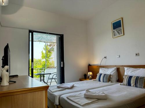 a bedroom with two beds and a desk and a balcony at Elgreco Apartment, at Tigaki, near the sea "3" in Tigaki