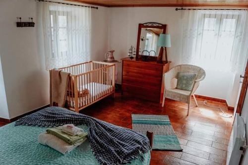 ein Schlafzimmer mit einem Bett, einem Spiegel und einem Kinderbett in der Unterkunft Casa da Milharica in Figueiró dos Vinhos