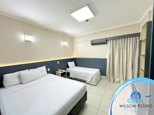 um quarto de hotel com duas camas e uma janela em Spazzio diRoma em Caldas Novas