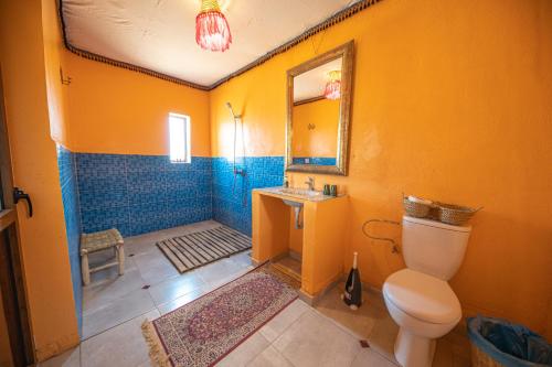 a bathroom with a toilet and a sink and a mirror at Les voix de Sahara Lodge in Mhamid