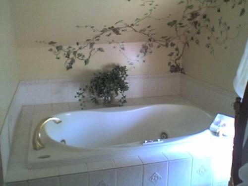 una vasca da bagno bianca con una pianta sul muro di Cleveland House Inn a Newport